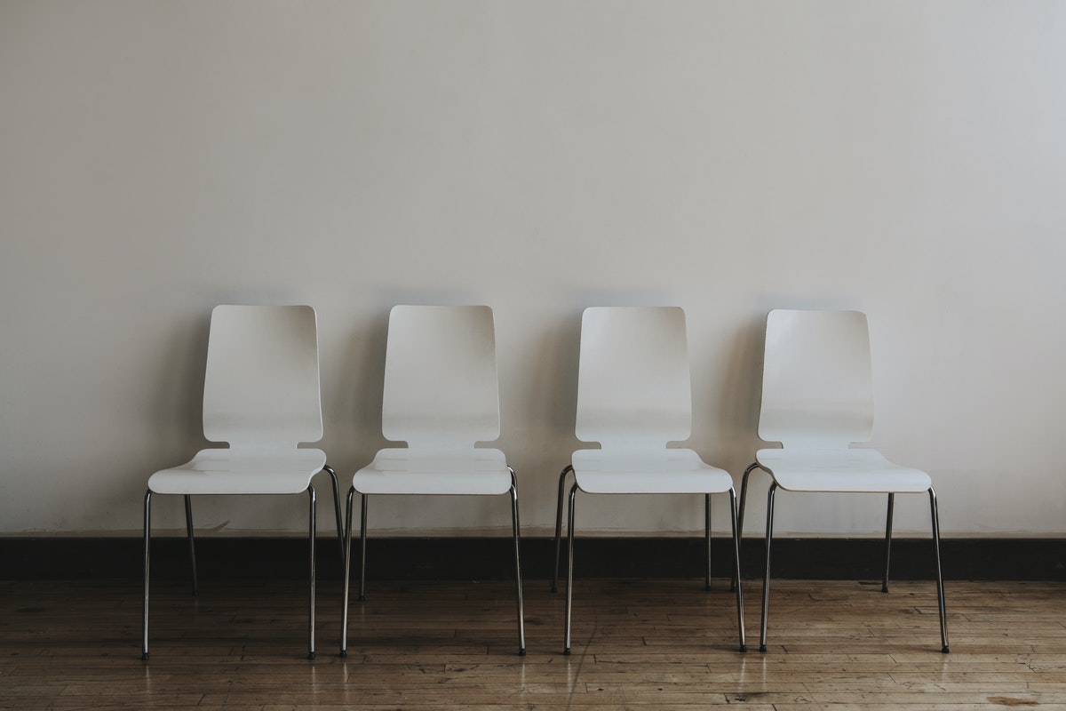 four white chairs against a white wall