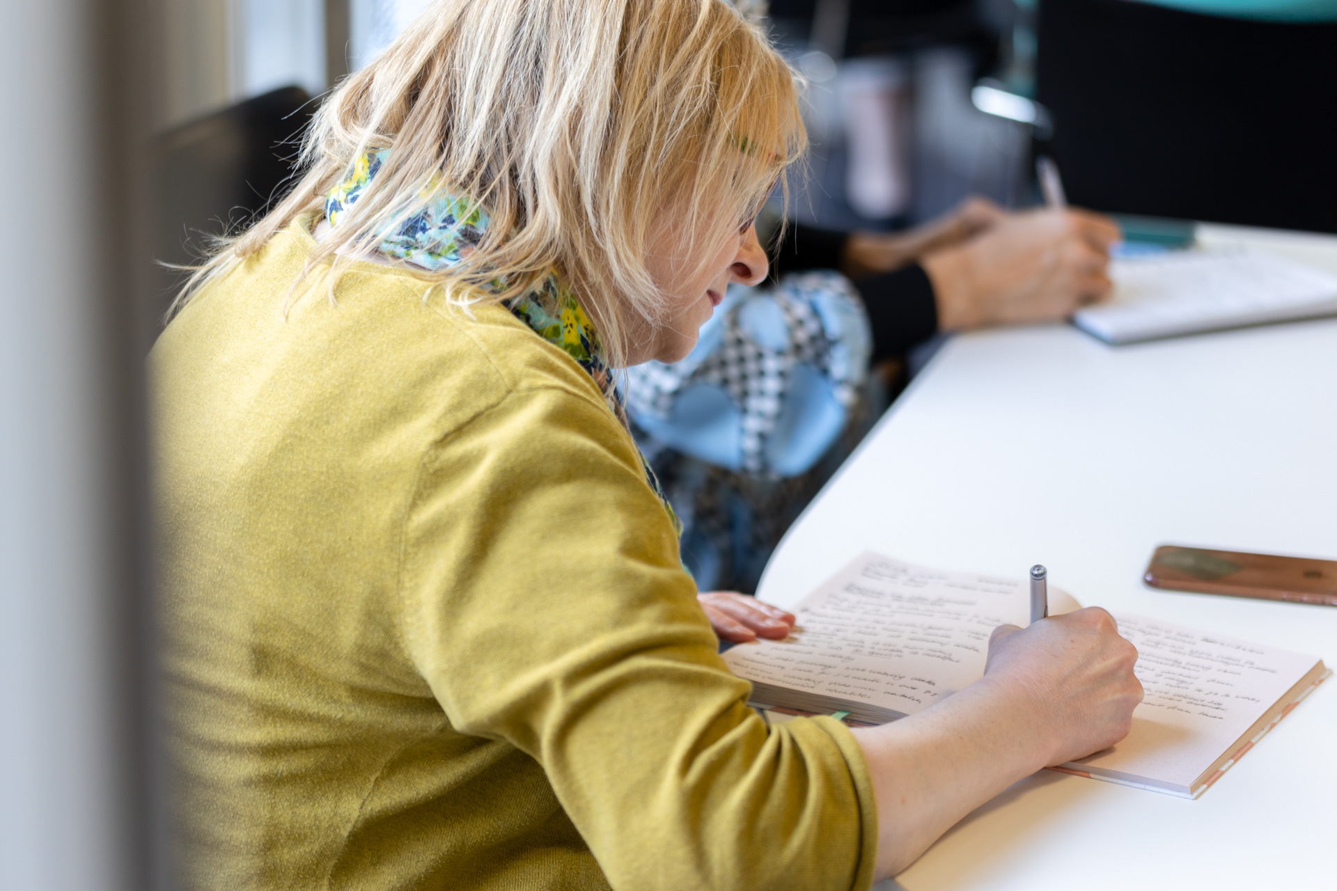 A woman sat writing at a desk