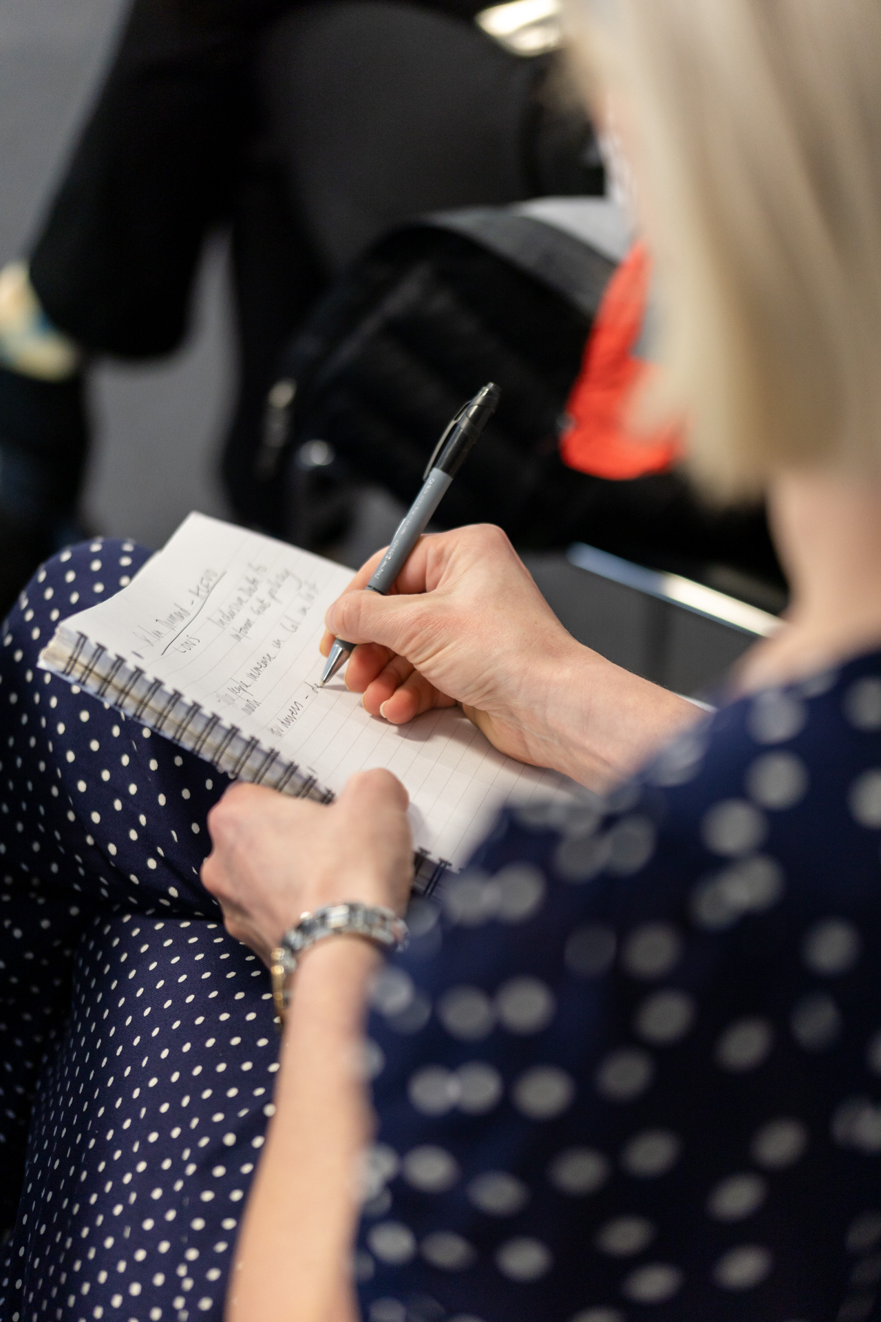 A close up photograph of woman writing in a pad with a pen